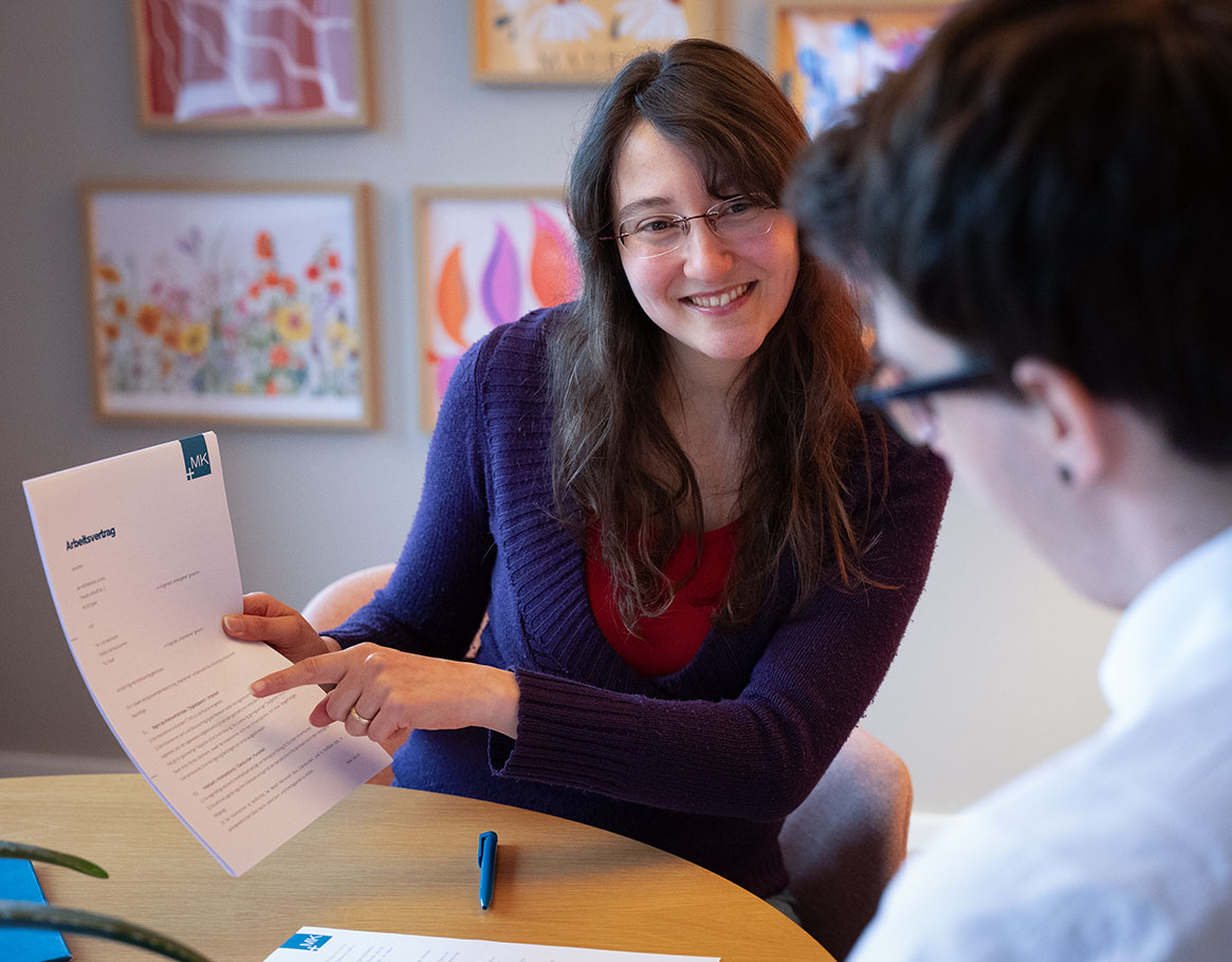 Vier junge Menschen, die an einem Tisch gemeinsam arbeiten, während sich zwei von ihnen begeistert ein High Five geben
